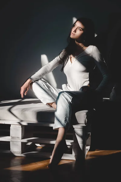 Portret van een mooie zachte vrouw in een wit bodysuit poserend in de zon. Zwart lang haar. sensualiteit en tederheid — Stockfoto