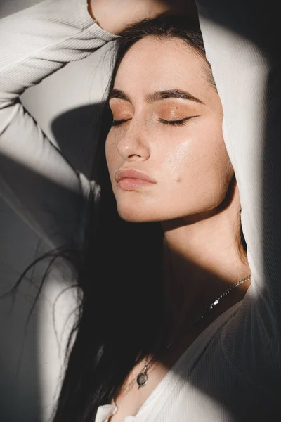 Portret van een mooie zachte vrouw in een wit bodysuit poserend in de zon. Zwart lang haar. sensualiteit en tederheid — Stockfoto