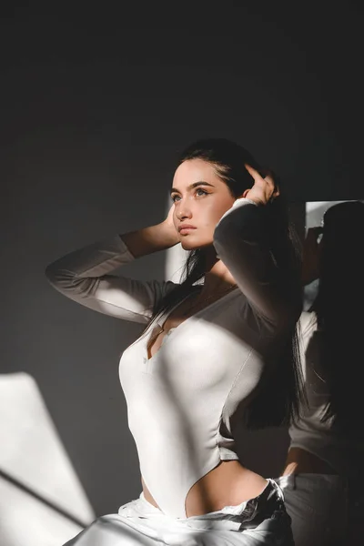 Retrato da bela mulher gentil em um bodysuit branco posando ao sol. Cabelo comprido preto. sensualidade e sensibilidade — Fotografia de Stock