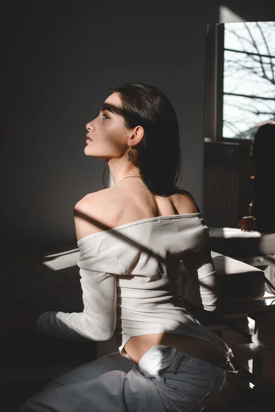 Portret van een mooie zachte vrouw in een wit bodysuit poserend in de zon. Zwart lang haar. sensualiteit en tederheid — Stockfoto