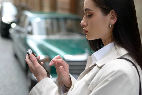 Una mujer en la calle usa un teléfono móvil. compras en línea. uso de aplicaciones móviles. —  Fotos de Stock