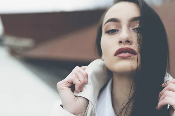 Outdoor portret van een jonge mooie modieuze dame in een stijlvolle jas. Het model kijkt opzij. Vrouwelijk modeconcept. Stadslevensstijl. Sluiten.. — Stockfoto