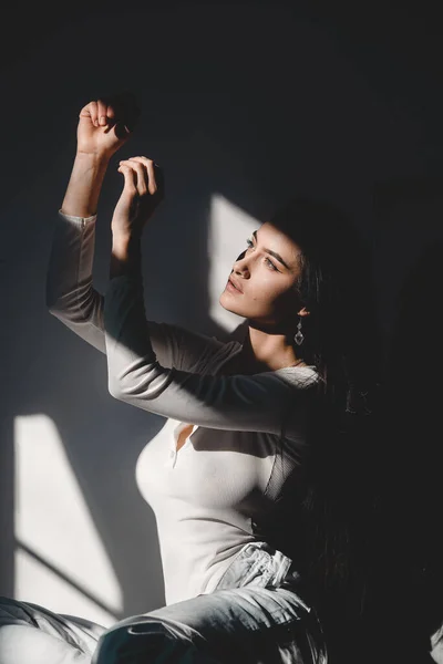 Portrait of beautiful gentle woman in a white bodysuit posing in the sunshine. Black long hair. sensuality and tenderness — Stock Photo, Image