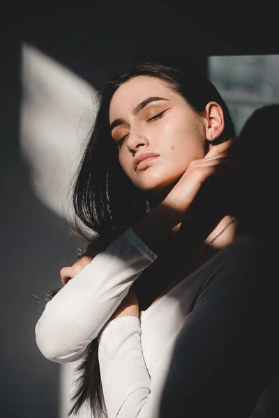 Güneş ışığında poz veren beyaz elbiseli güzel bir kadının portresi. Siyah uzun saçlı. şehvet ve şefkat — Stok fotoğraf