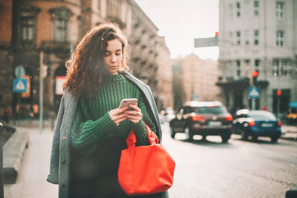 Una mujer en la calle usa un teléfono móvil. compras en línea. uso de aplicaciones móviles. Clima lluvioso. — Foto de Stock