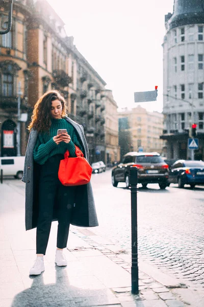 Una mujer en la calle usa un teléfono móvil. compras en línea. uso de aplicaciones móviles. Clima lluvioso. — Foto de Stock