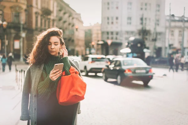 Uma mulher na rua usa um telemóvel. compras online. Utilização de aplicações móveis. Tempo chuvoso. — Fotografia de Stock