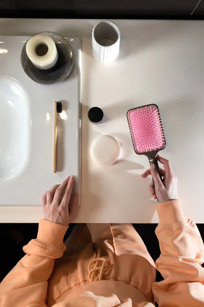 Top view of bathroom accessories, toothbrush near hair brush, bow, mobile phone and face sponge on a white surface — Stock Photo, Image