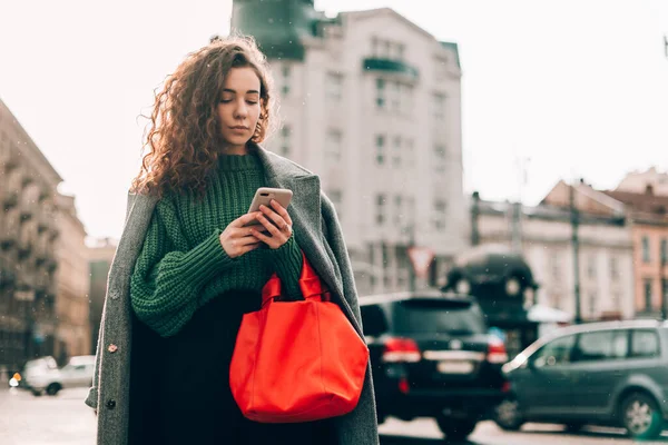 Una mujer en la calle usa un teléfono móvil. compras en línea. uso de aplicaciones móviles. Clima lluvioso. Grano de película. Ruido — Foto de Stock