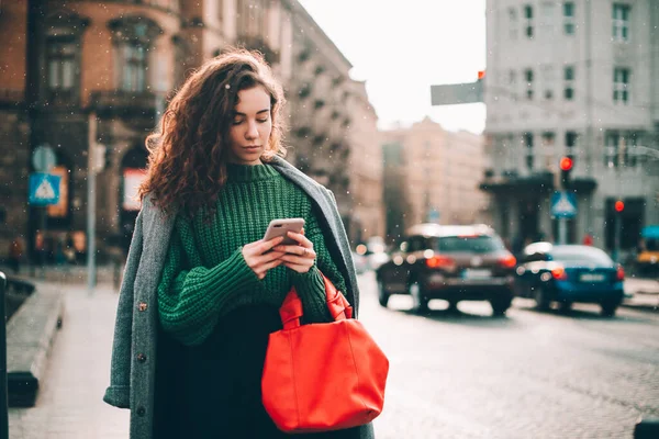 Una mujer en la calle usa un teléfono móvil. compras en línea. uso de aplicaciones móviles. Clima lluvioso. Grano de película. Ruido — Foto de Stock