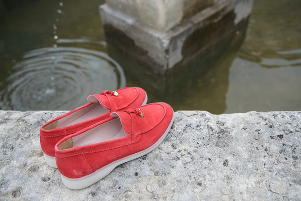 Zapatos mocasines de gamuza con estilo rojo para mujer en el fondo de piedra. Par de zapatos de mocasines femeninos de moda, al aire libre — Foto de Stock