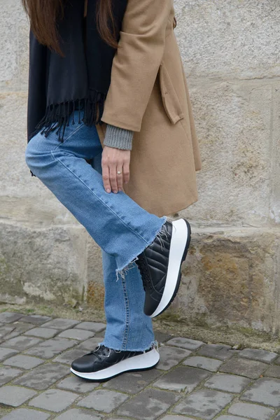 Chica joven con estilo posando. Ella está usando un abrigo beige, jeans y zapatos deportivos de cuero con estilo — Foto de Stock