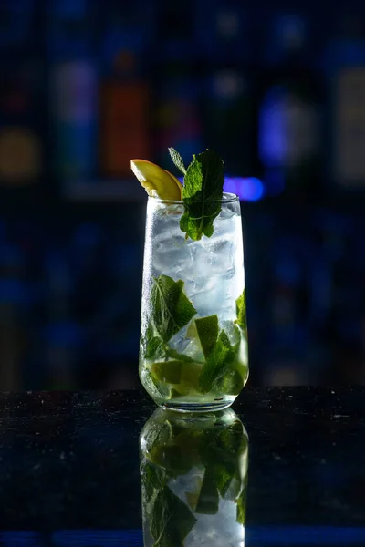 summer alcoholic cocktail mojito with rum, mint, lime and ice, bar tools, gray background, selective focus