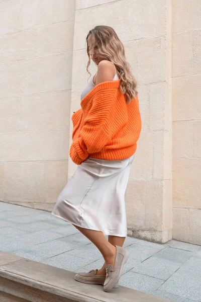 주황색 스웨터를 입고 길거리에서 포즈를 취하는 유행하는 여성의 모습 — 스톡 사진
