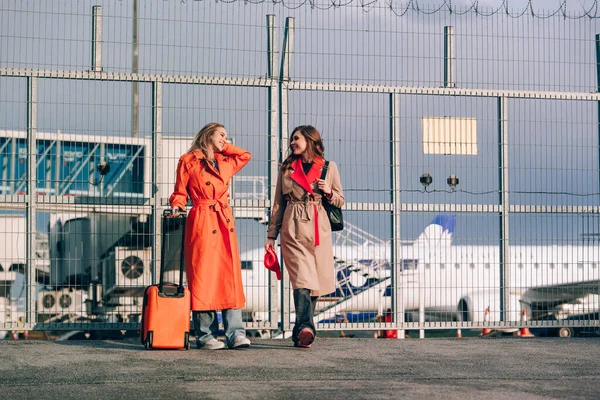 Havaalanının yakınında bavullarıyla yürüyen iki mutlu kız. Hava yolculuğu, yaz tatili. — Stok fotoğraf