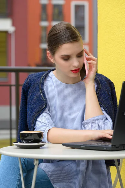 Charming happy woman student communicates by phone and use laptop computer to prepare for the course work. — Stock Photo, Image