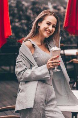 Bir kadının eli, tazeleyici bir kokteyli tüple bardakta tutar..