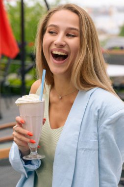 Bir kadının eli, tazeleyici bir kokteyli tüple bardakta tutar..