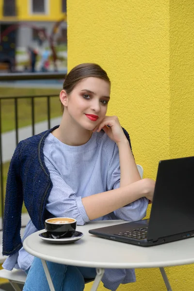 Обаятельная счастливая студентка, использующая ноутбук для подготовки к курсовой работе. — стоковое фото