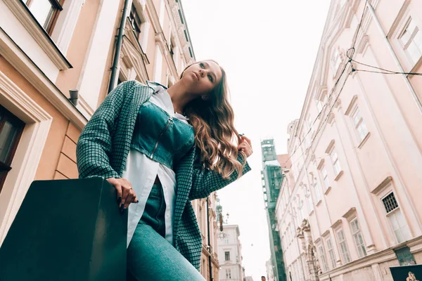 Mujer en un jeanse azul, camisa blanca y abrigo a cuadros de moda posando en la calle. — Foto de Stock