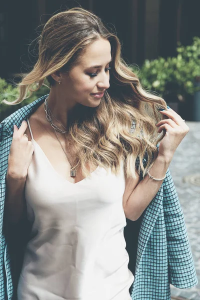 Mulher nova na moda com cabelo loiro vestido com vestido bege e casaco xadrez posando. — Fotografia de Stock