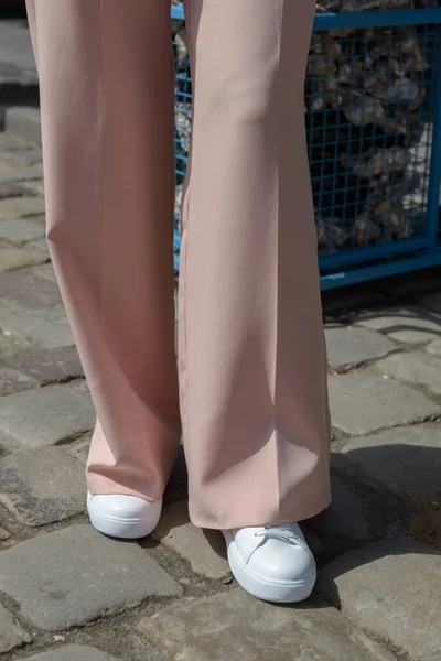 Mujer con estilo en zapatillas blancas de moda zapatos y pantalones beige paseos por la ciudad. — Foto de Stock