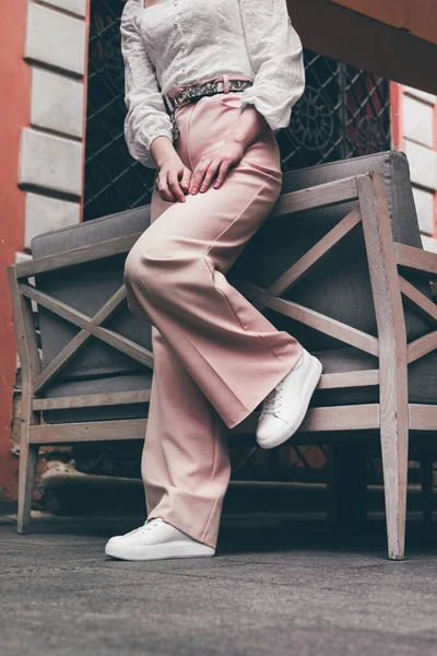 Modaya uygun beyaz spor ayakkabılı şık bir kadın. Ayakkabılar ve bej pantolonlar şehirde dolaşıyor.. — Stok fotoğraf