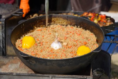 Büyük kazanda geleneksel pilav pişirme, açık havada sokak yemeği.