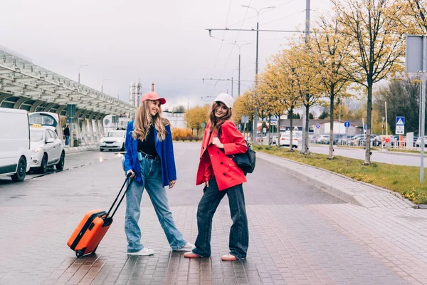Duas meninas felizes andando perto do aeroporto, com bagagem. Viagens aéreas, férias de verão — Fotografia de Stock
