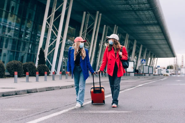 Dos chicas felices caminando cerca del aeropuerto, con equipaje. Viajes aéreos, vacaciones de verano —  Fotos de Stock