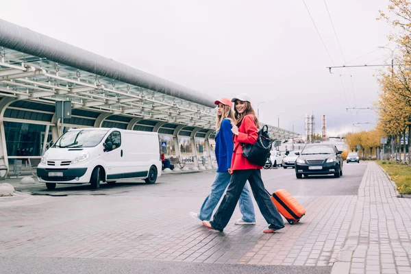 Duas meninas felizes andando perto do aeroporto, com bagagem. Viagens aéreas, férias de verão — Fotografia de Stock