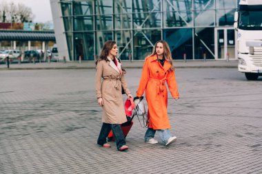 Havaalanının yakınında bavullarıyla yürüyen iki mutlu kız. Hava yolculuğu, yaz tatili.