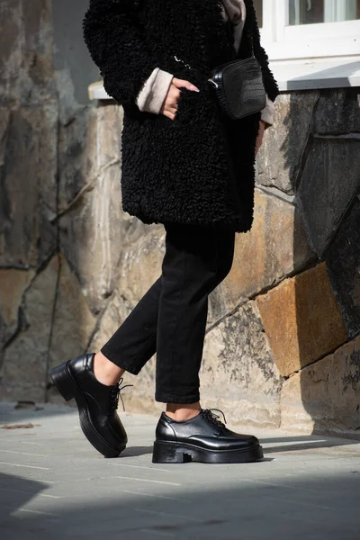 Närbild foto av ung vacker kvinna i svart päls, jeanse och skor på stadens gata — Stockfoto
