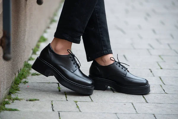 Foto de cerca de una mujer joven con abrigo de piel negra, jeanse y zapatos en la calle de la ciudad — Foto de Stock