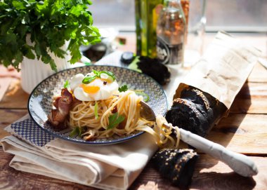 Makarna Carbonara pastırma ve yumurta ile plaka üzerinde koyu ahşap b pulluklar