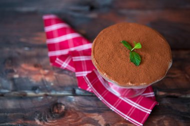 Koyu ahşap arka plan üzerinde kırmızı peçeteye tiramisu. Geleneksel 