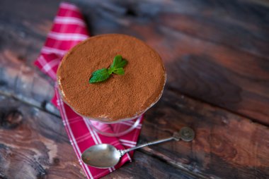 Koyu ahşap arka plan üzerinde kırmızı peçeteye tiramisu. Geleneksel 