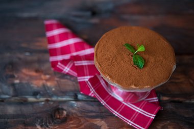 Koyu ahşap arka plan üzerinde kırmızı peçeteye tiramisu. Geleneksel 