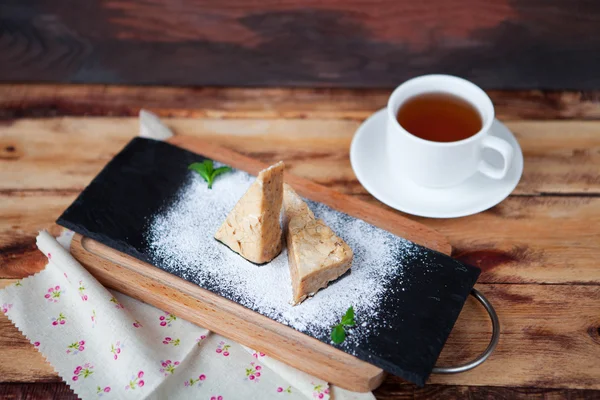 Kue almond manis dengan secangkir teh dengan latar belakang kayu tua — Stok Foto