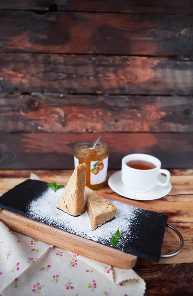 Kue almond manis dengan secangkir teh dengan latar belakang kayu tua — Stok Foto