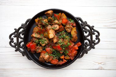 Beyaz ahşap zemin üzerinde tava üzerinde sebze ile lezzetli et