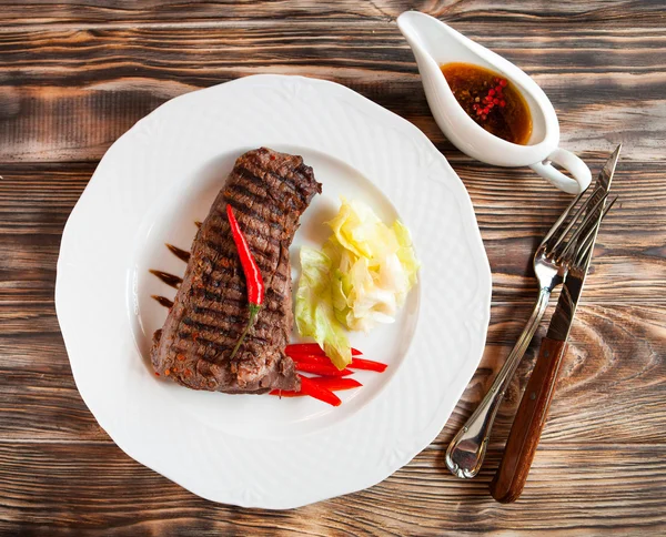 Steakes νόστιμα βοδινό με τσίλι σε άσπρο πιάτο στην ξύλινη πλάτη — Φωτογραφία Αρχείου