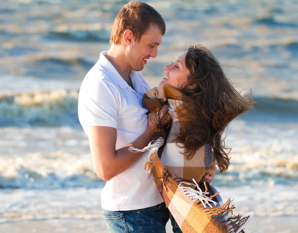 Ungt par i kärlek på stranden insvept i en filt. — Stockfoto