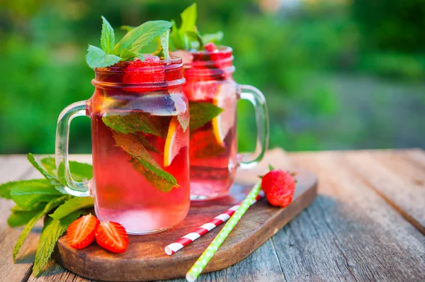 Red lemonade with strawberries and mint on an old wooden table i — Stock Photo, Image