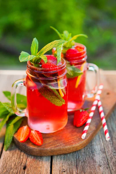 Red lemonade with strawberries and mint on an old wooden table i — Stock Photo, Image