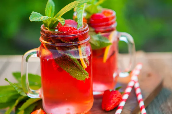 Limonade rouge aux fraises et menthe sur une vieille table en bois i — Photo