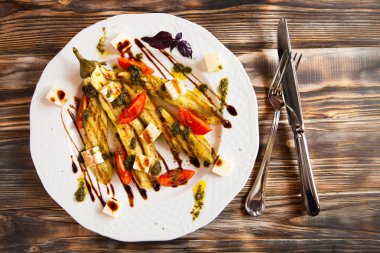 Kızarmış sebze iliği ve beyaz tabakta domates