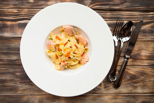 Pasta fettuccine with salmon and caviar on a white dish on a woo — Stock Photo, Image