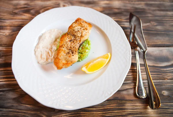 Poisson grillé avec tranche de citron et saucisse blanche sur fond en bois — Photo