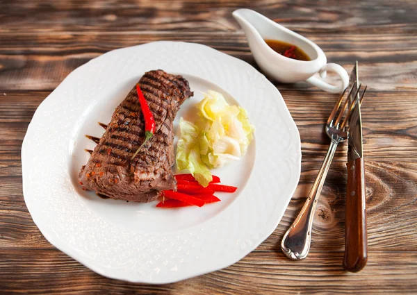 Steakes νόστιμα βοδινό με τσίλι σε άσπρο πιάτο στην ξύλινη πλάτη — Φωτογραφία Αρχείου